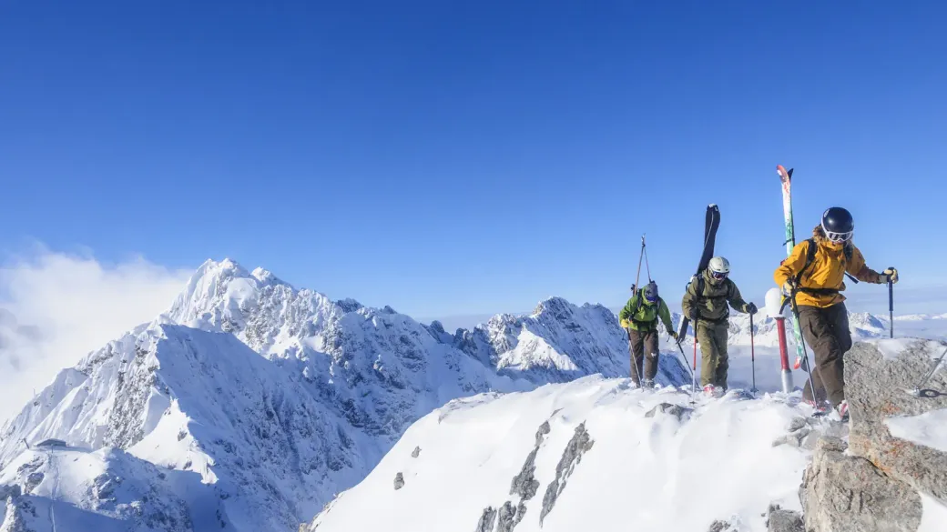 Une cordée de skieurs-alpinistes atteint un sommet enneigé