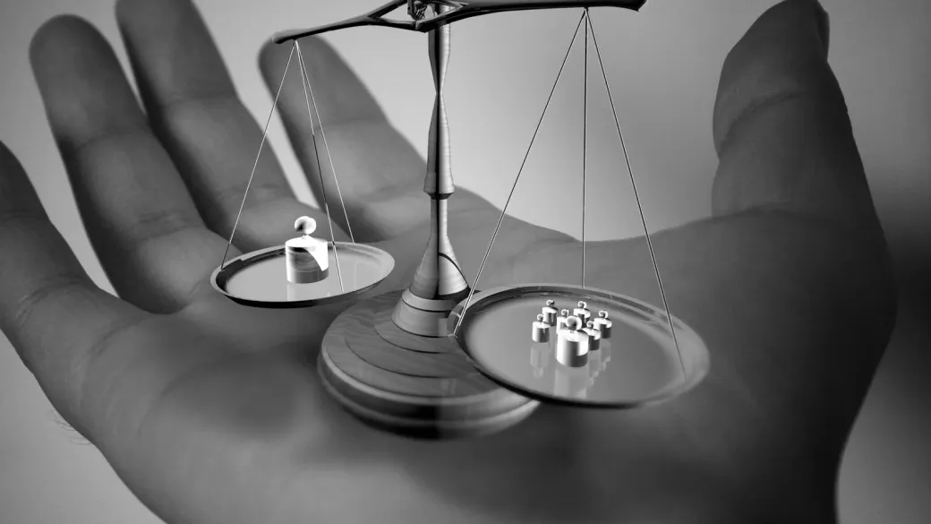 Une balance miniature posée dans la paume d'une main, en noir et blanc