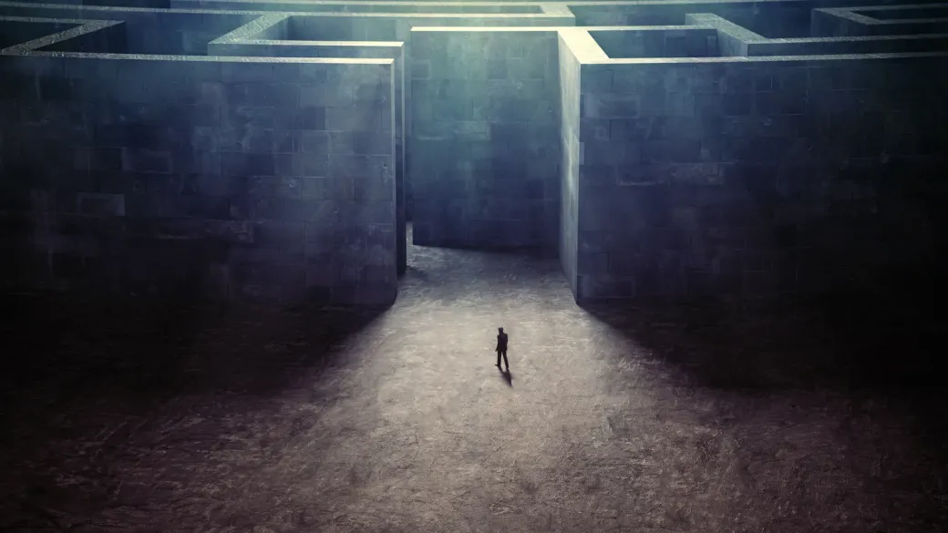 Eine einzelne Person am Eingang eines riesigen Labyrinths aus Steinmauern